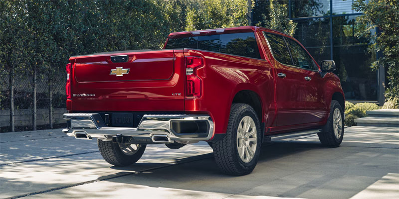 Red Chevrolet Silverado pickup truck parked outdoors with a rear three-quarter view.